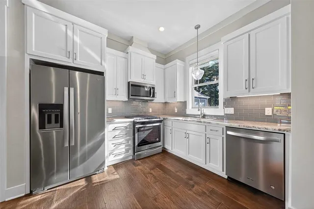 a kitchen with granite countertop a refrigerator stove and sink