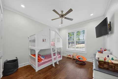 a bedroom with furniture a flat screen tv and a window