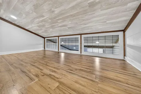 a view of an empty room with wooden floor and fan