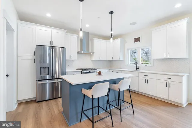 a kitchen with stainless steel appliances granite countertop a refrigerator a sink dishwasher a stove and white cabinets with wooden floor