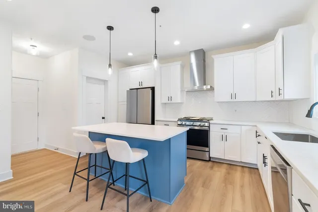 a kitchen with stainless steel appliances granite countertop a sink a stove a refrigerator and island with wooden floor