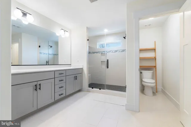 a spacious bathroom with a granite countertop sink a toilet and a mirror