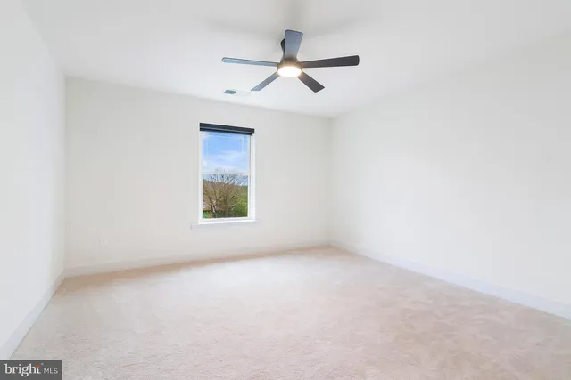 an empty room with a window and a fan