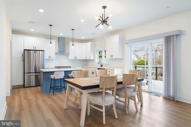 a kitchen with stainless steel appliances a dining table chairs and wooden floor