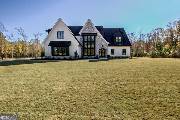 a front view of house with yard and trees in the background