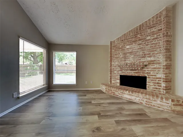 a view of an empty room with a fireplace and a window