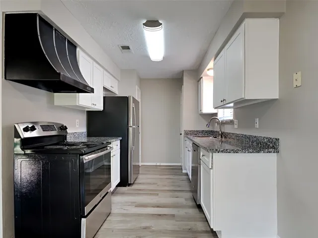 a kitchen with stainless steel appliances granite countertop a stove a sink and a refrigerator