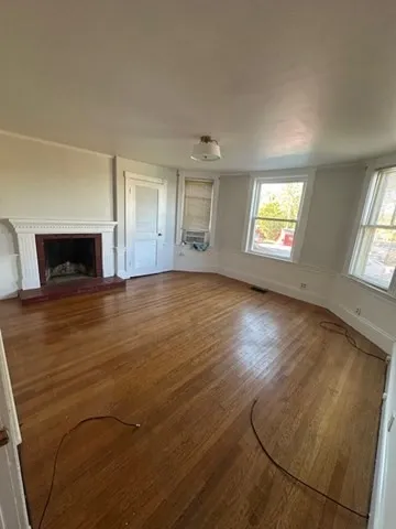 an empty room with windows and fireplace