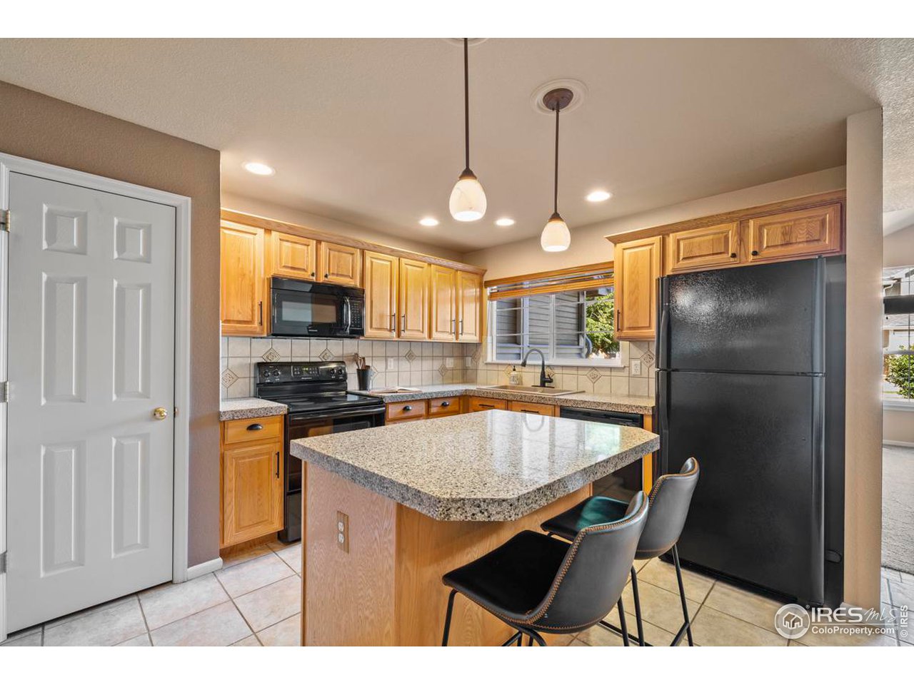 115 Bayside Circle Windsor, CO 80550 - Photo 8 of 23 a kitchen with stainless steel appliances kitchen island granite countertop a refrigerator a stove a sink a dining table and chairs with wooden floor