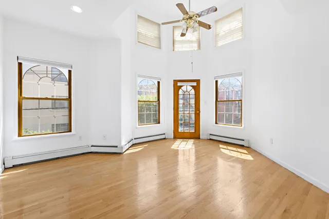 a view of an empty room with a window and wooden floor
