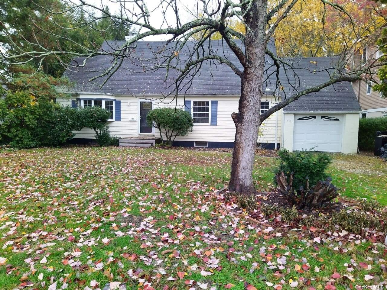 a view of a house with a small yard and a large tree