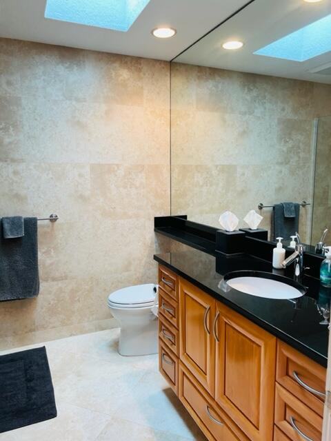 400 River Edge Road Jupiter, FL 33477 - Photo 9 of 19 a bathroom with a granite countertop sink a toilet a mirror and shower