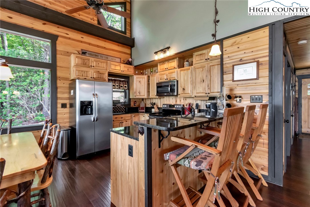 4879 Staghorn Road Purlear, NC 28665 - Photo 21 of 50 a kitchen with stainless steel appliances a stove top oven a refrigerator a dining table and chairs with wooden floor