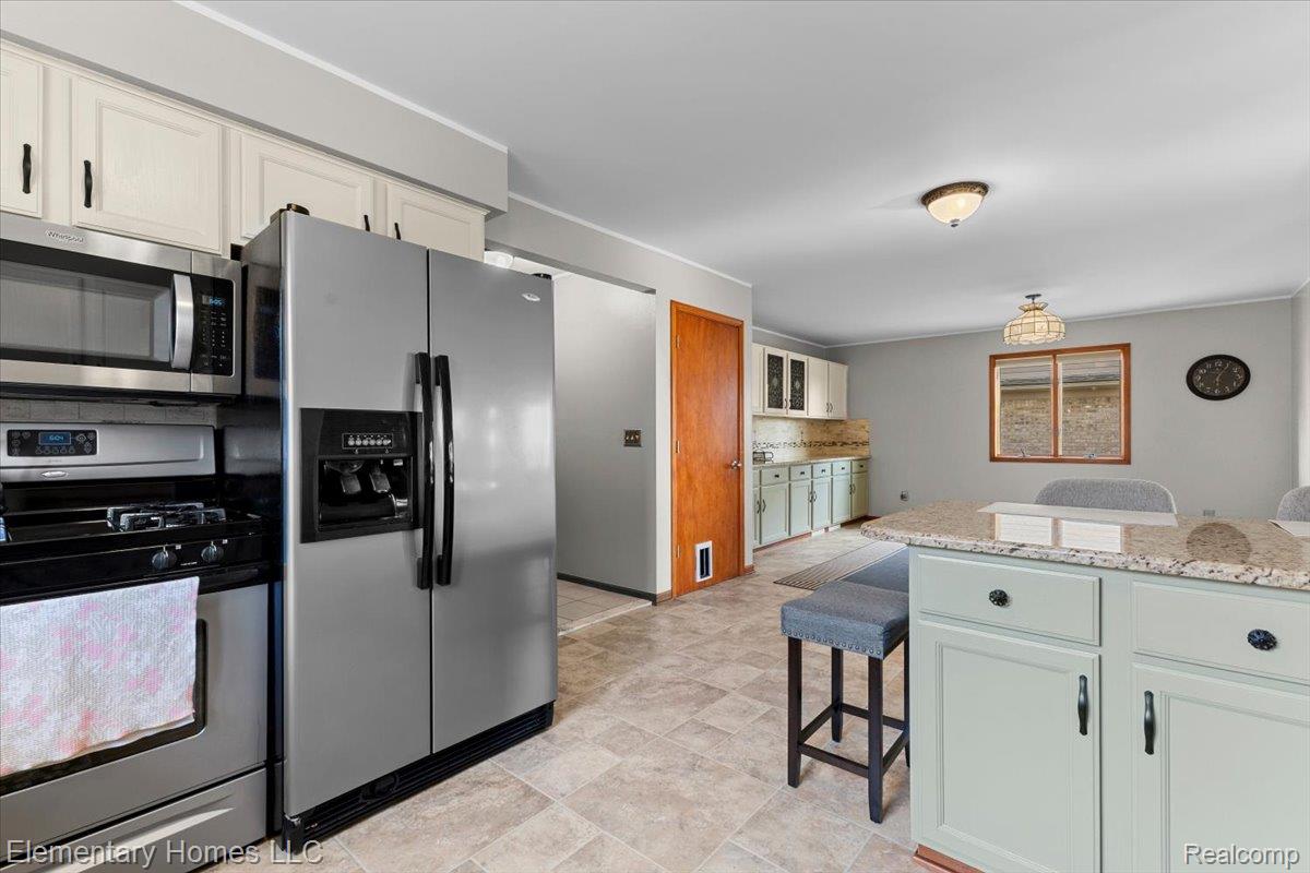 51637 Baker Road New Baltimore, MI 48047 - Photo 21 of 47 Kitchen with stainless steel appliances, light stone counters, ornamental molding, and stone finish flooring