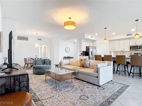a living room with furniture kitchen view and a chandelier