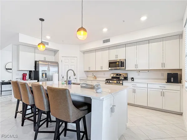 a kitchen with stainless steel appliances granite countertop a stove top oven a sink dishwasher and white cabinets with wooden floor