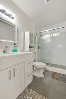 a bathroom with a granite countertop toilet a sink a mirror and shower