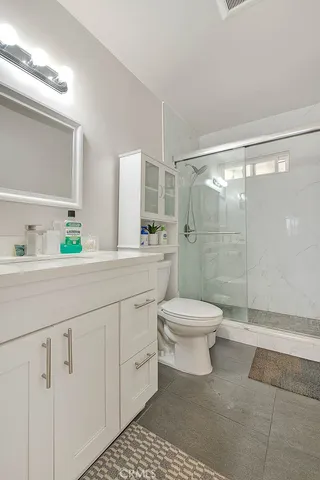 a bathroom with a granite countertop toilet a sink a mirror and shower