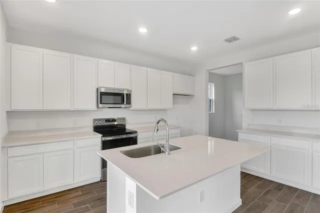 a kitchen with a sink white cabinets and stainless steel appliances