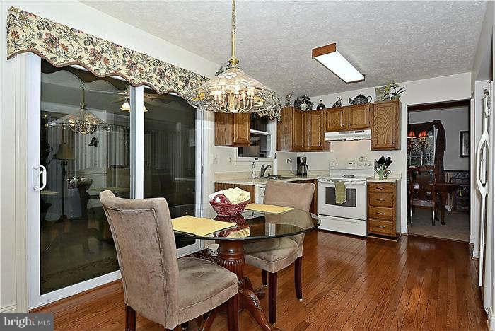 8102 Walton Road Severn, MD 21144 - Photo 9 of 30 a dining room with wooden floor a chandelier a wooden table and chairs