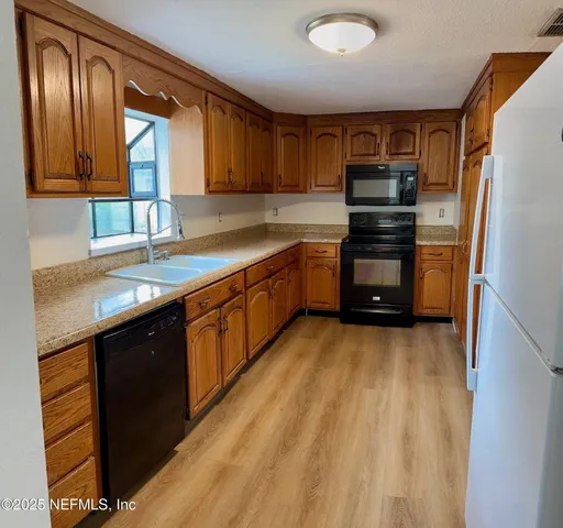 a kitchen with stainless steel appliances a sink cabinets and a wooden floor