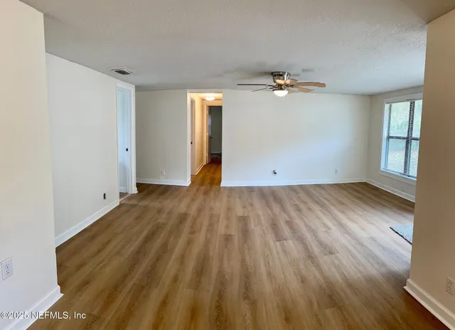 an empty room with wooden floor and windows
