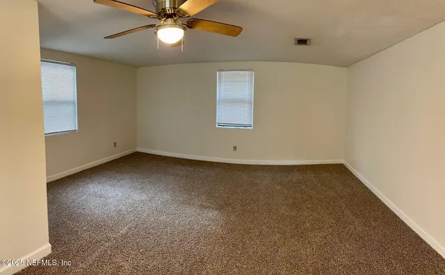 an empty room with a fan & a window