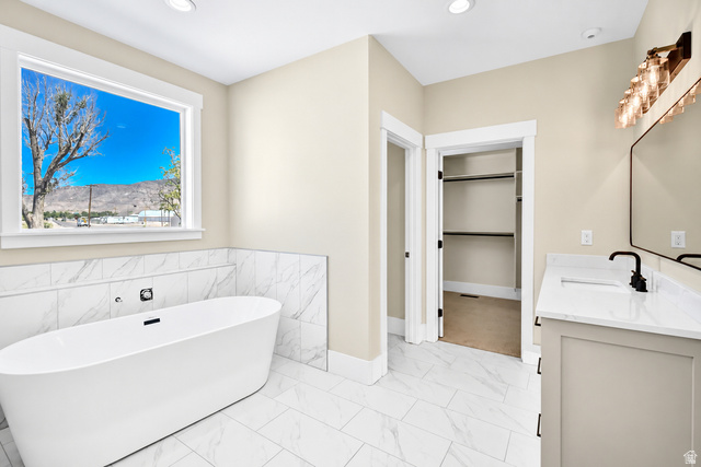 840 South Jones Road Monroe, UT 84754 - Photo 16 of 52 Freestanding soaking tub, large window, tile flooring, vanity with countertop, and modern light fixture