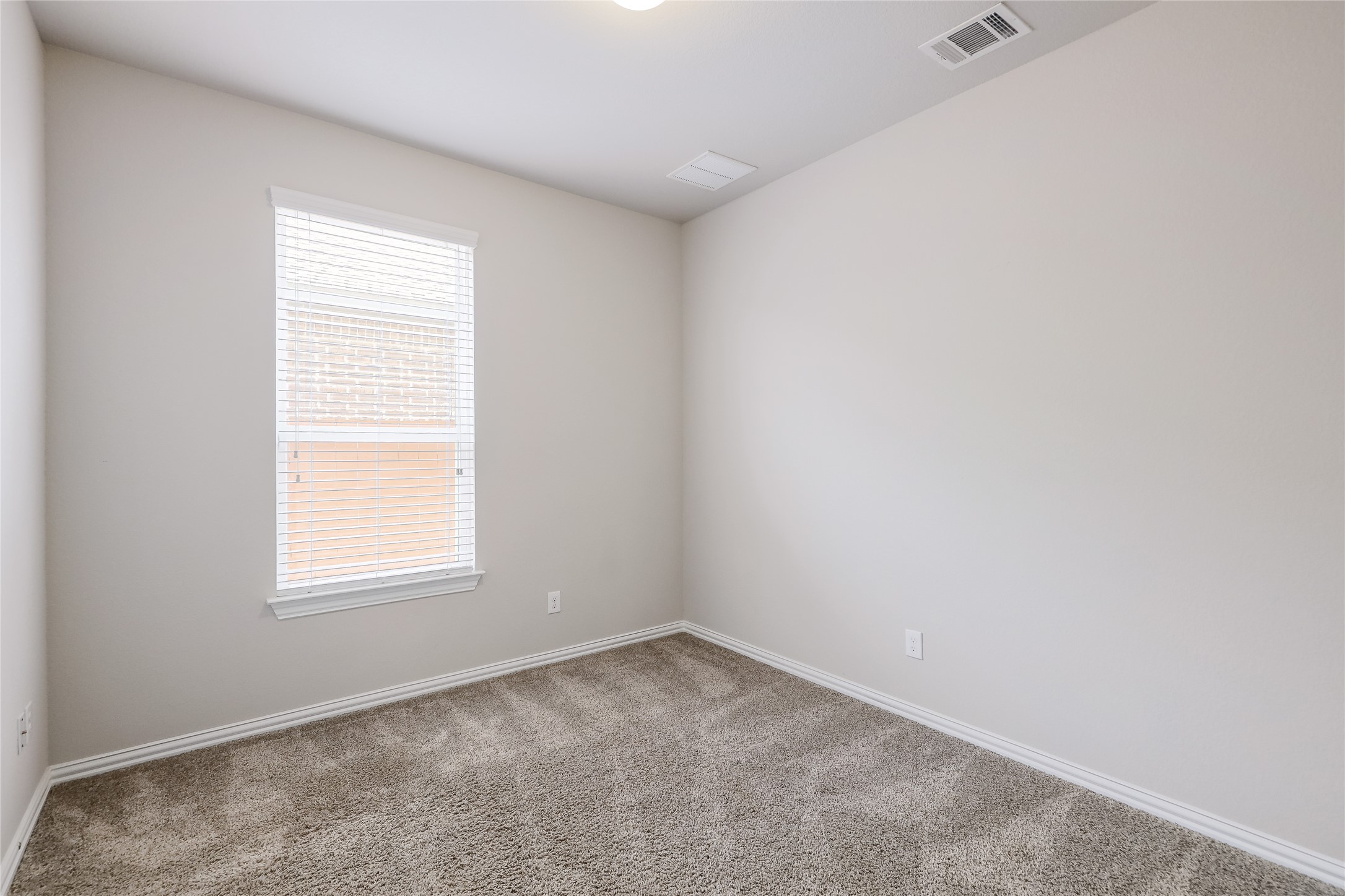 205 Penna Lane Georgetown, TX 78628 - Photo 19 of 32 A well-lit bedroom features plush carpeting and a window with blinds, creating a comfortable atmosphere.