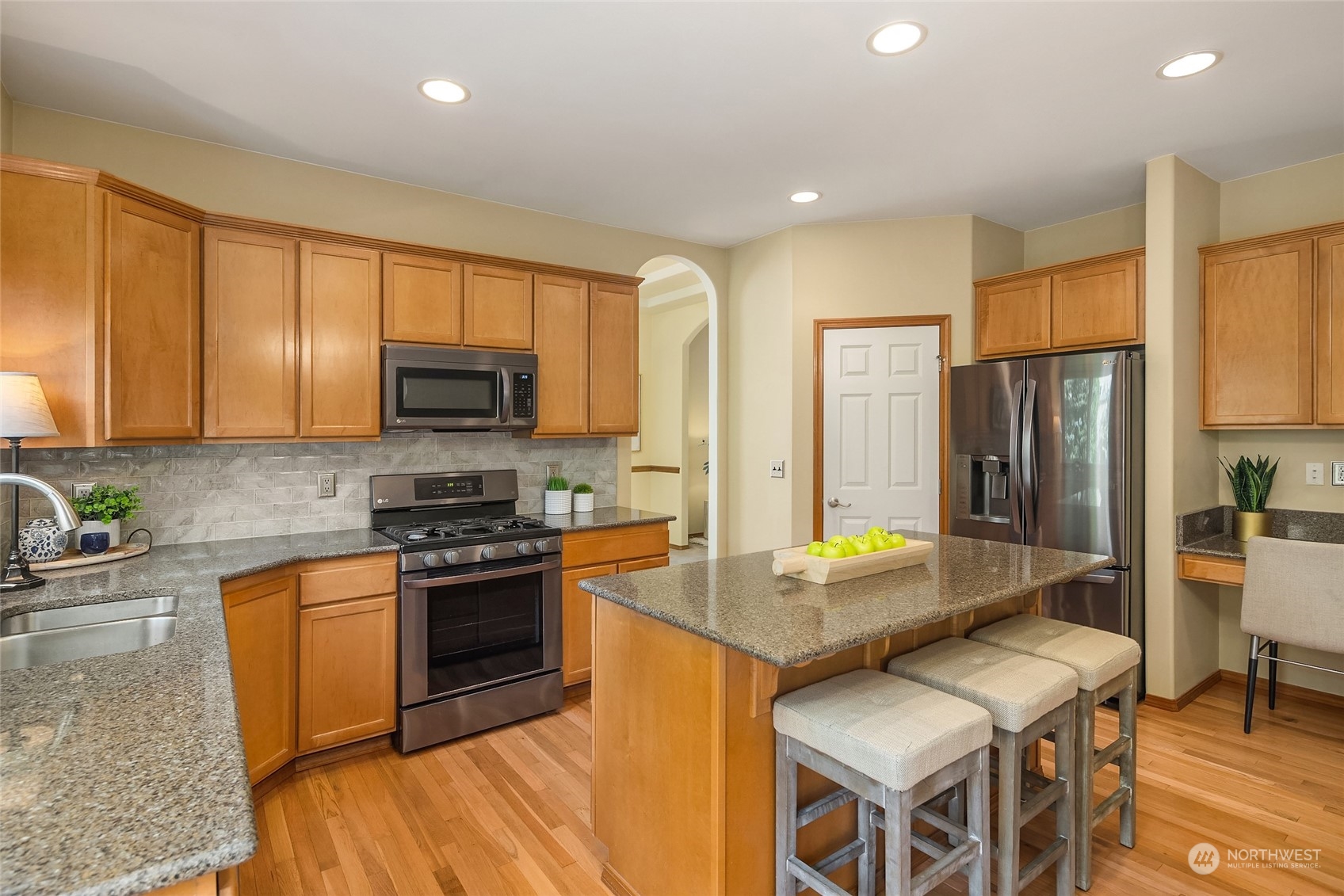 307 197th Place Southwest Bothell, WA 98012 - Photo 8 of 30 a kitchen with stainless steel appliances granite countertop a stove top oven a sink dishwasher a dining table and chairs with wooden floor
