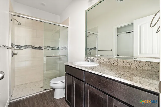 a bathroom with a granite countertop sink a toilet a mirror and shower