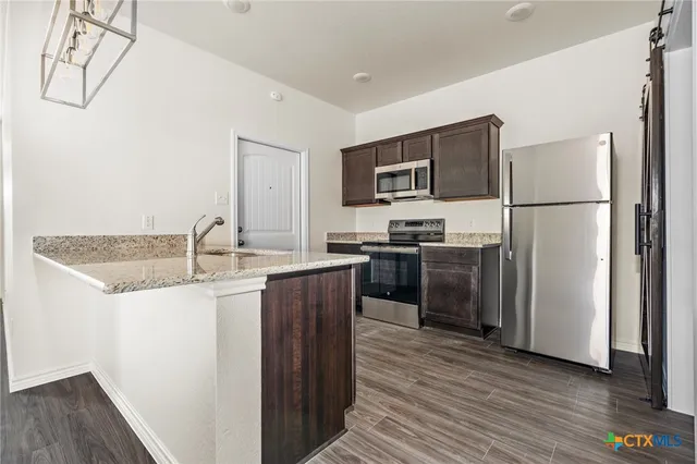 a kitchen with kitchen island a sink stainless steel appliances and refrigerator