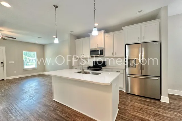 a kitchen with kitchen island a sink appliances a counter space and a window