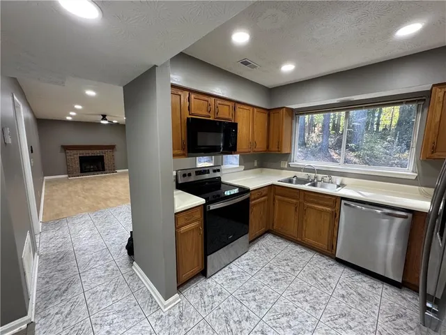 a large kitchen with stainless steel appliances granite countertop a stove a sink and a microwave