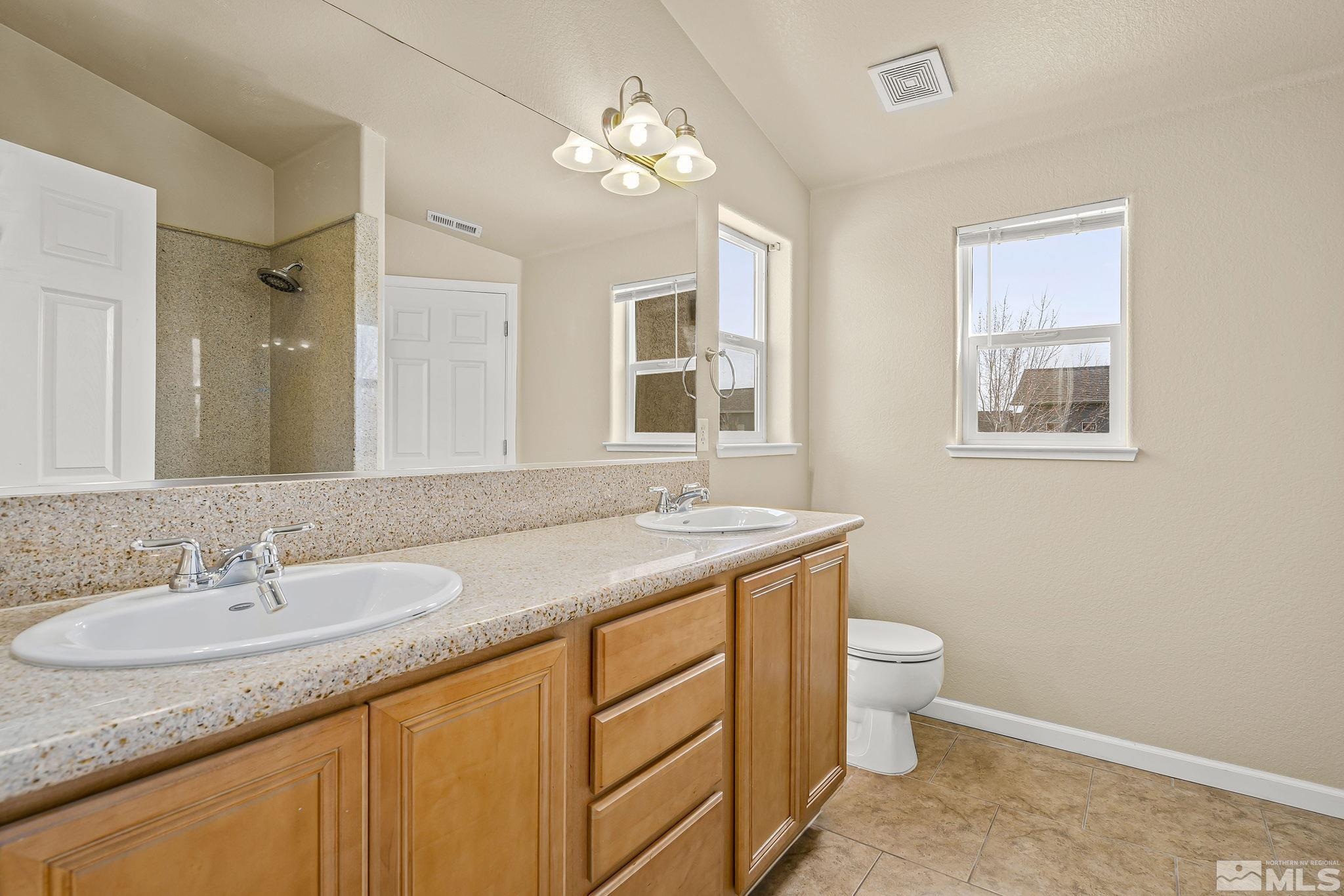 1026 Floral Ridge Way Sparks, NV 89436 - Photo 15 of 22 a bathroom with a granite countertop sink a toilet and a mirror