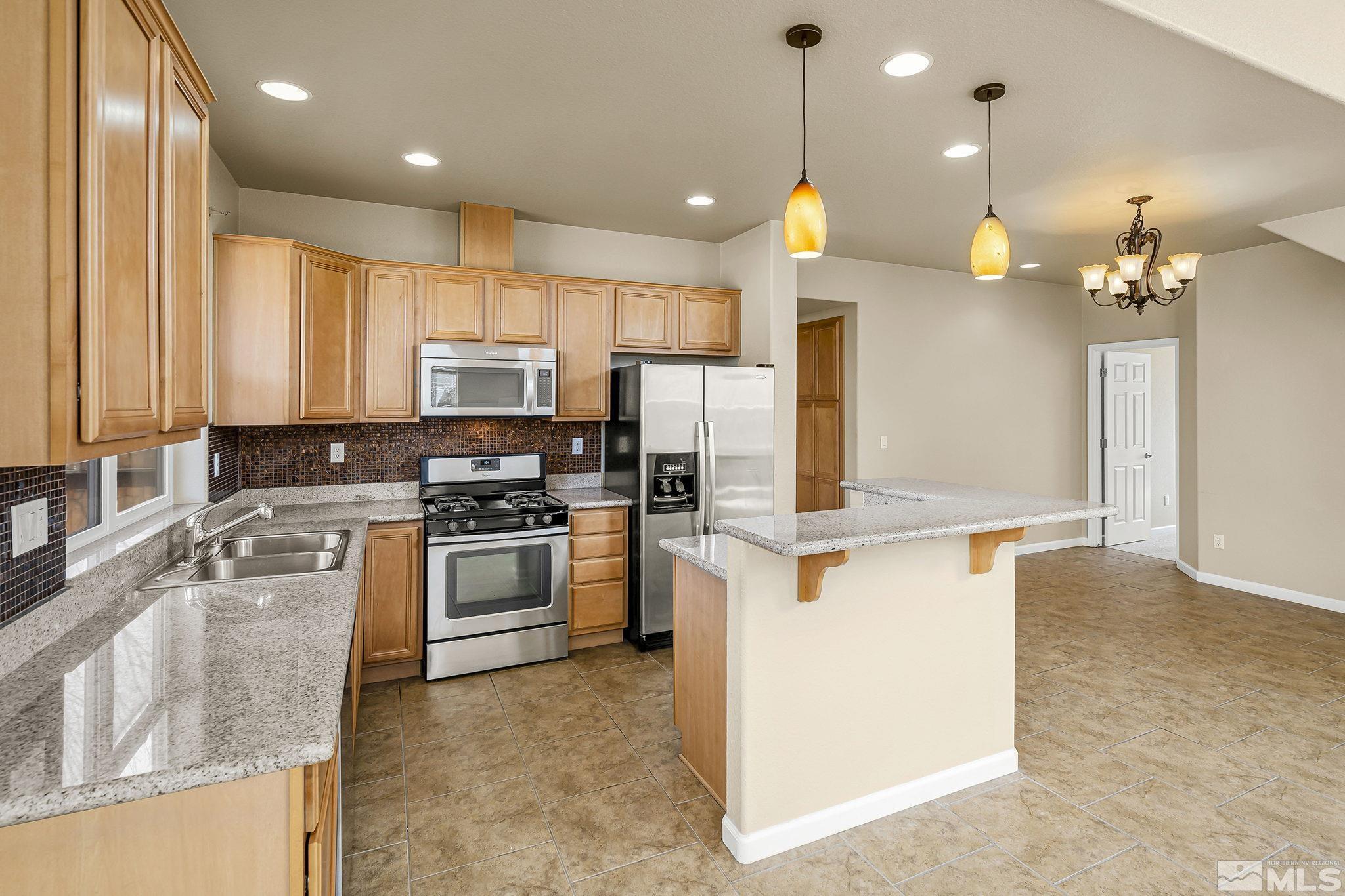 1026 Floral Ridge Way Sparks, NV 89436 - Photo 8 of 22 a kitchen with kitchen island a stove a sink a center island and a window