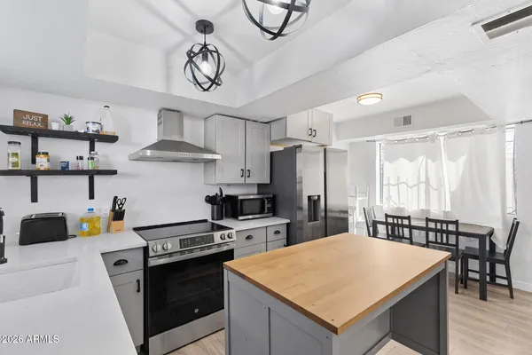 a kitchen with stainless steel appliances a stove a refrigerator a sink a dining table and chairs with wooden floor