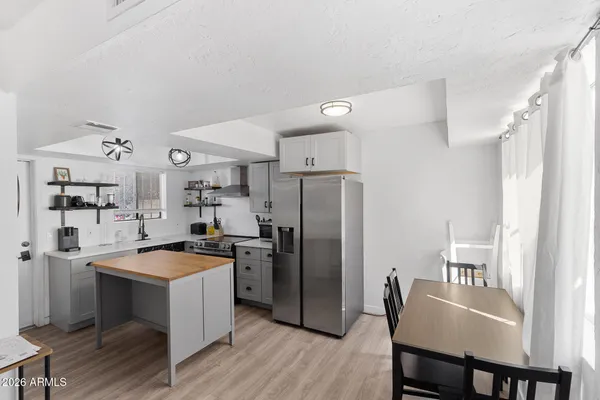 a kitchen with stainless steel appliances granite countertop a refrigerator a sink dishwasher a stove and a dining table with wooden floor