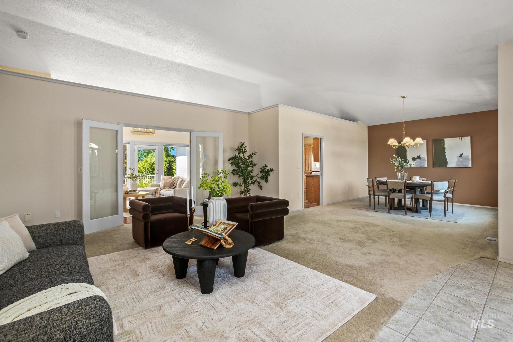 15181 Drury Way Caldwell, ID 83607 - Photo 10 of 49 Spacious living area featuring vaulted ceilings, light-toned carpeting, and a separate dining area with a brass chandelier