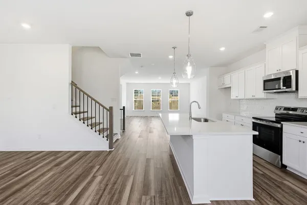 a view of a kitchen with cabinets stainless steel appliances a sink and a center island
