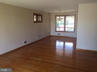 1522 Burnfield Road Baltimore, MD 21237 - Photo 2 of 20 a view of an empty room with wooden floor and a window