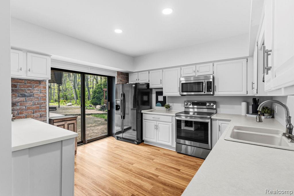 11111 Hibner Road Hartland, MI 48353 - Photo 14 of 59 Kitchen with stainless steel appliances, light wood finished floors, light countertops, white cabinets, and recessed lighting