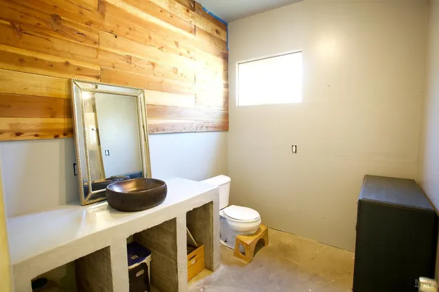 a bathroom with a sink a toilet a chair and a window