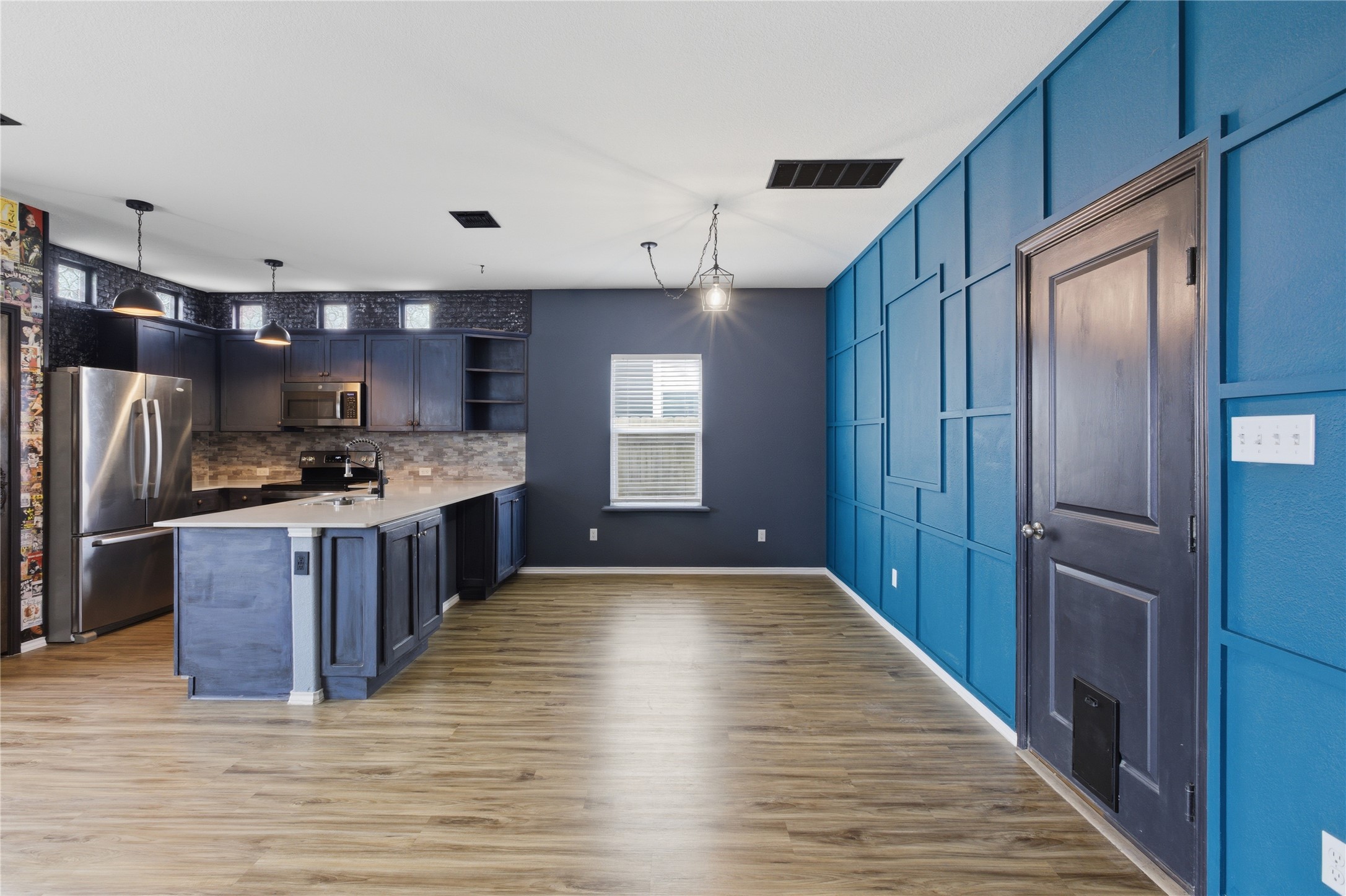 116 Night Riders Way Jarrell, TX 76537 - Photo 18 of 40 Open-concept kitchen and living area featuring wood-finish flooring, a kitchen island with stone-finish countertop, stainless steel appliances, pendant lighting, and a decorative paneled wall