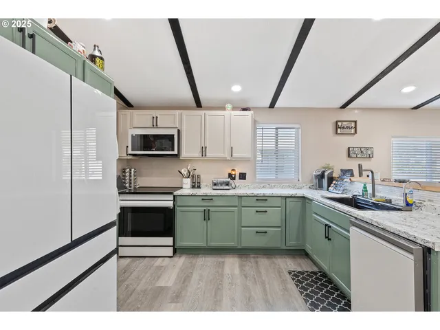 a kitchen with stainless steel appliances granite countertop a sink a stove a microwave a refrigerator a sink and dishwasher