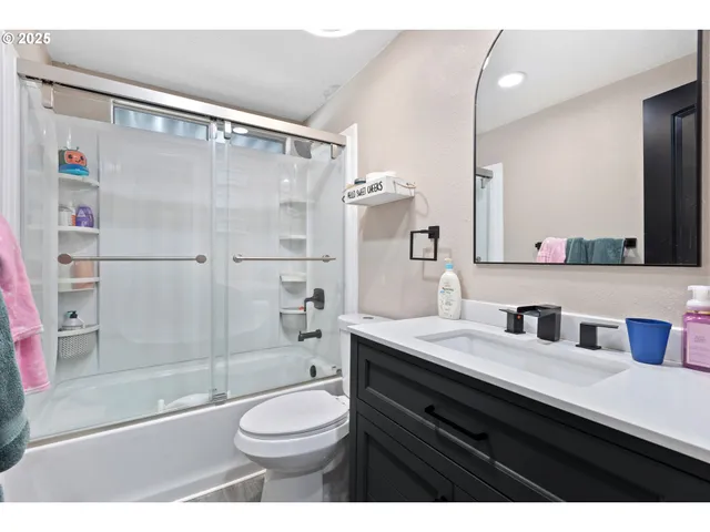 a bathroom with a sink a toilet a mirror and shower