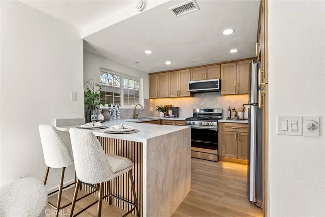 a kitchen with kitchen island granite countertop a stove top oven a sink dishwasher and a refrigerator with wooden floor