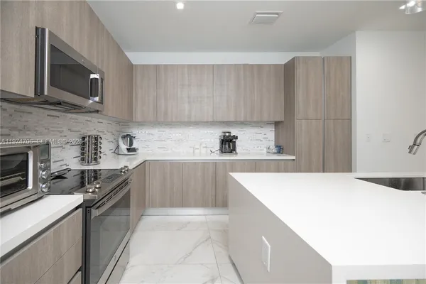 a kitchen with stainless steel appliances a refrigerator sink and microwave