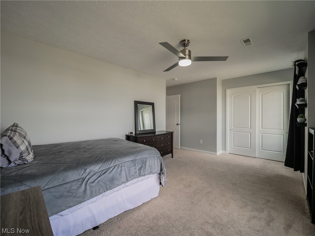 37571 Amber Way North Ridgeville, OH 44039 - Photo 22 of 35 Bedroom featuring ceiling fan, a closet, light colored carpet, and a textured ceiling