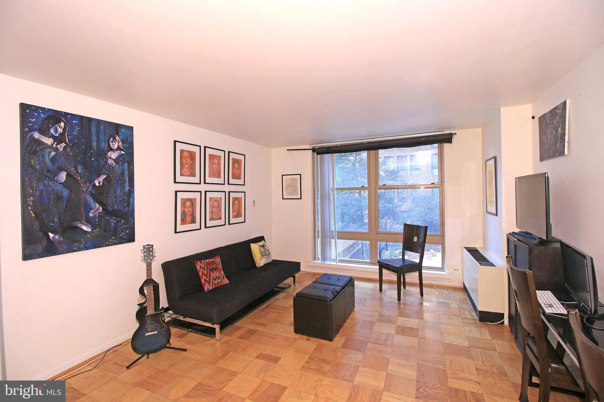 1260 21st Street Northwest, Unit 207 Washington, DC 20036 - Photo 1 of 16 a living room with furniture a flat screen tv and a refrigerator